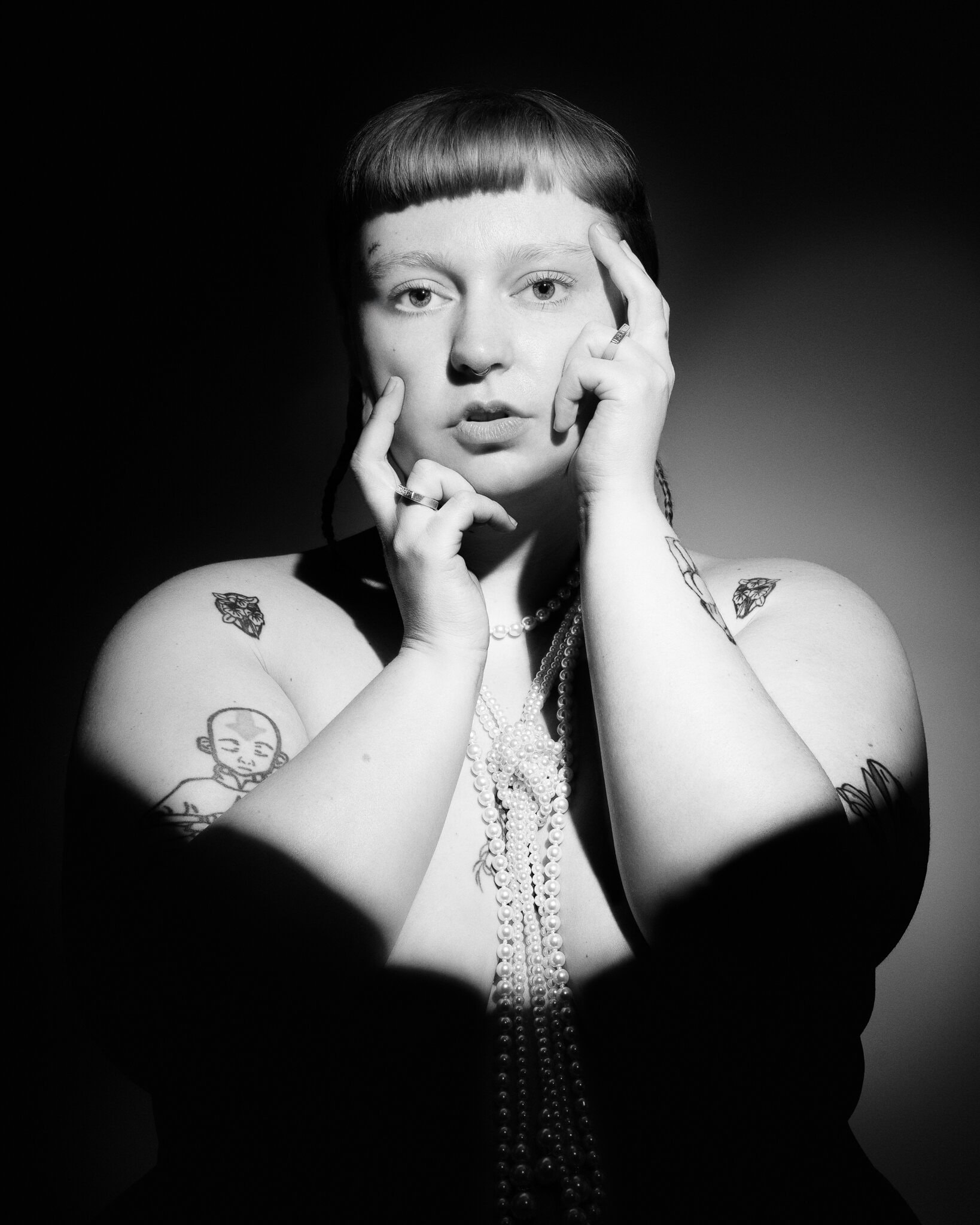 Creative black-and-white portrait of a woman wearing layered pearls, photographed by a London portrait photographer.