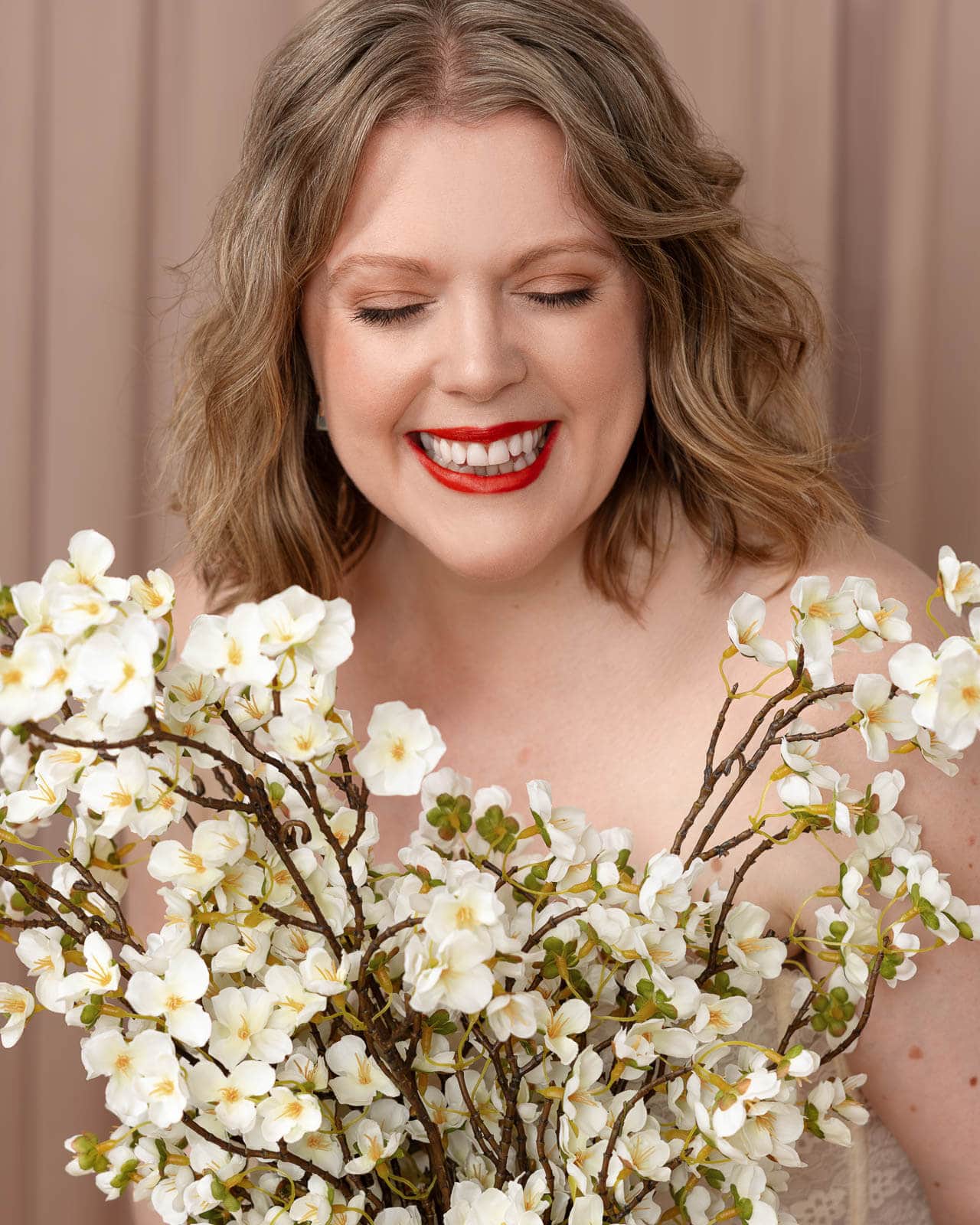 Siorna Ashby, London boudoir photographer, smiling amongst white flowers